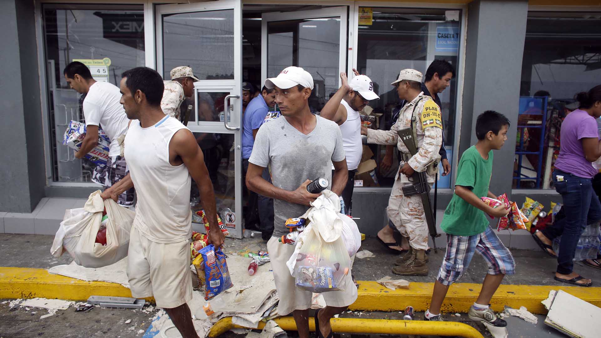 People loot a convenience store destroyed by Hurricane Odile, in Los Cabos, Mexico, Monday, Sept. 15, 2014. Hurricane Odile hammered Mexico's Baja California Peninsula overnight, damaging homes and tearing away the facades of luxury resorts, shattering countless car and hotel windows and leaving lobbies swamped and full of debris on Monday. (AP Photo/Victor R. Caivano)
